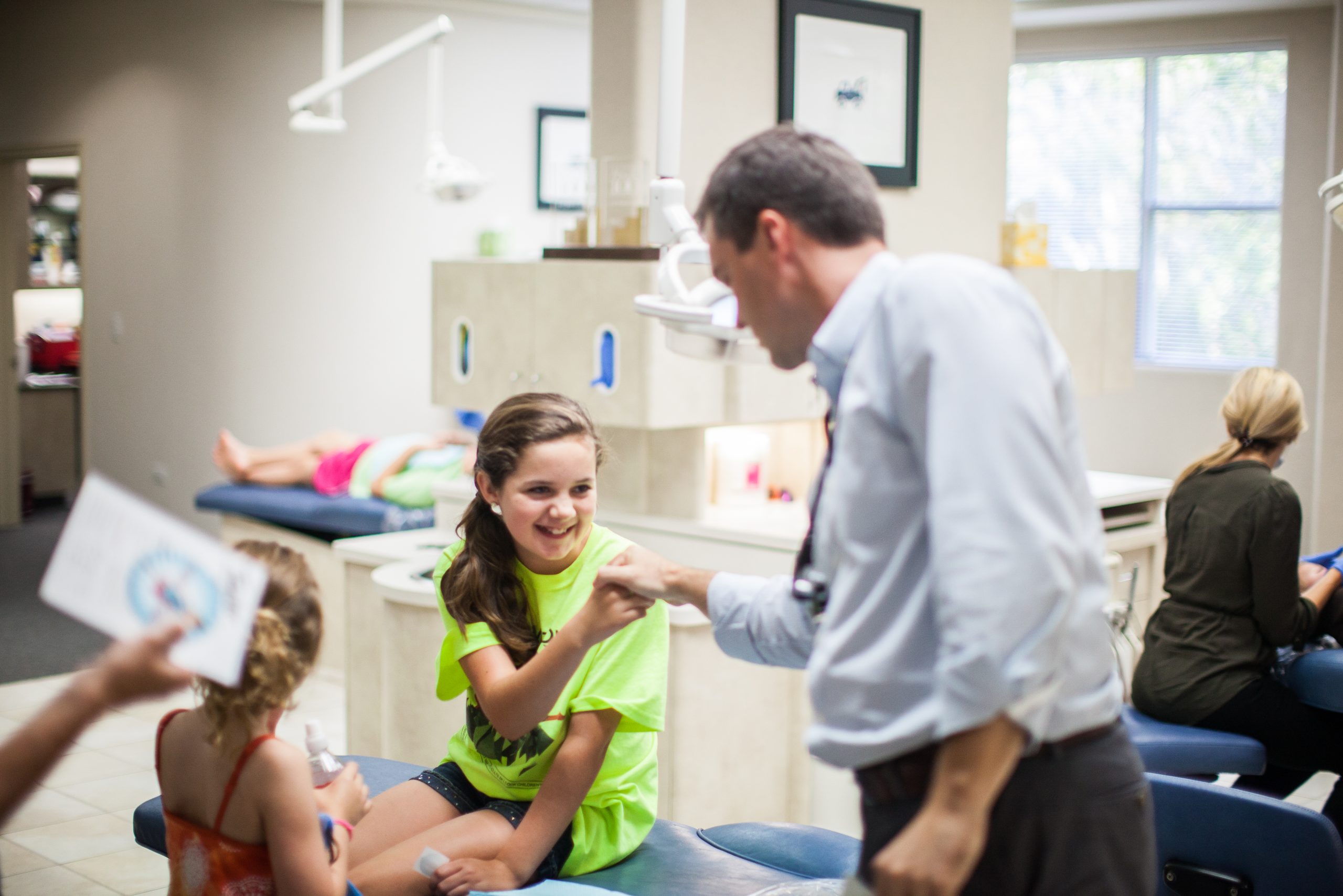 Dentist high-fiving a smiling young patient in a bright treatment room