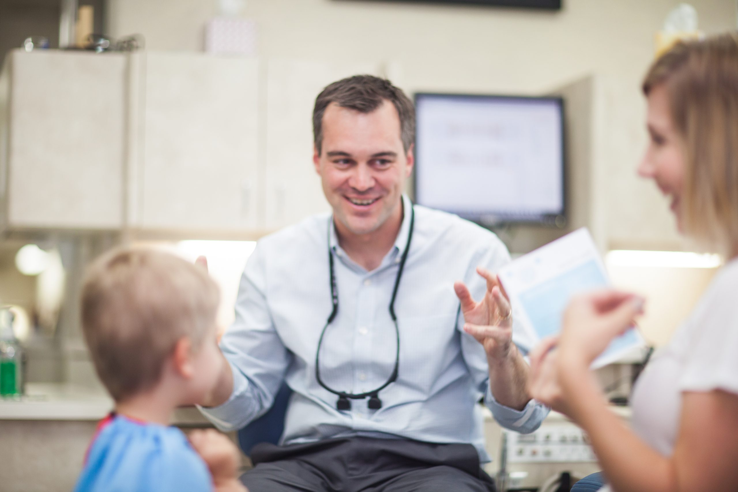 Dentist high-fiving a smiling young patient in a bright treatment room